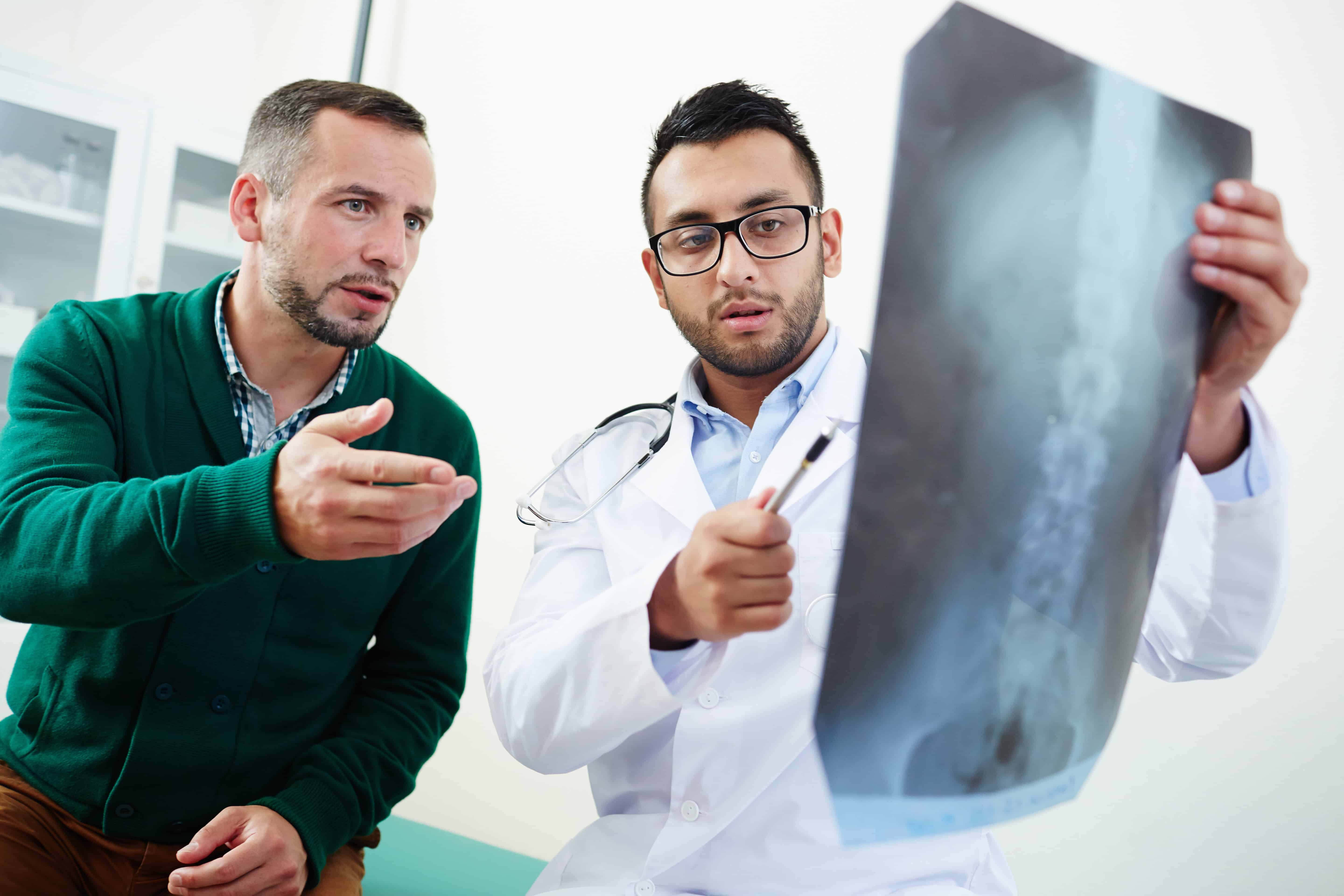 Chiropractor looking at x-ray explaining to patient meaningof lumbar x-ray and lower back pain. Chiropractic inner west clinic setting. Dulwich Hill Chiropractor